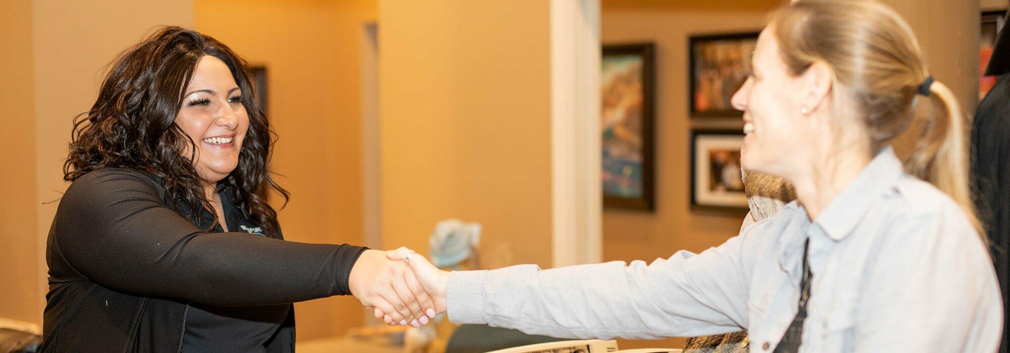 A woman shakes hands with another woman in the Holland Landing Dentist office.