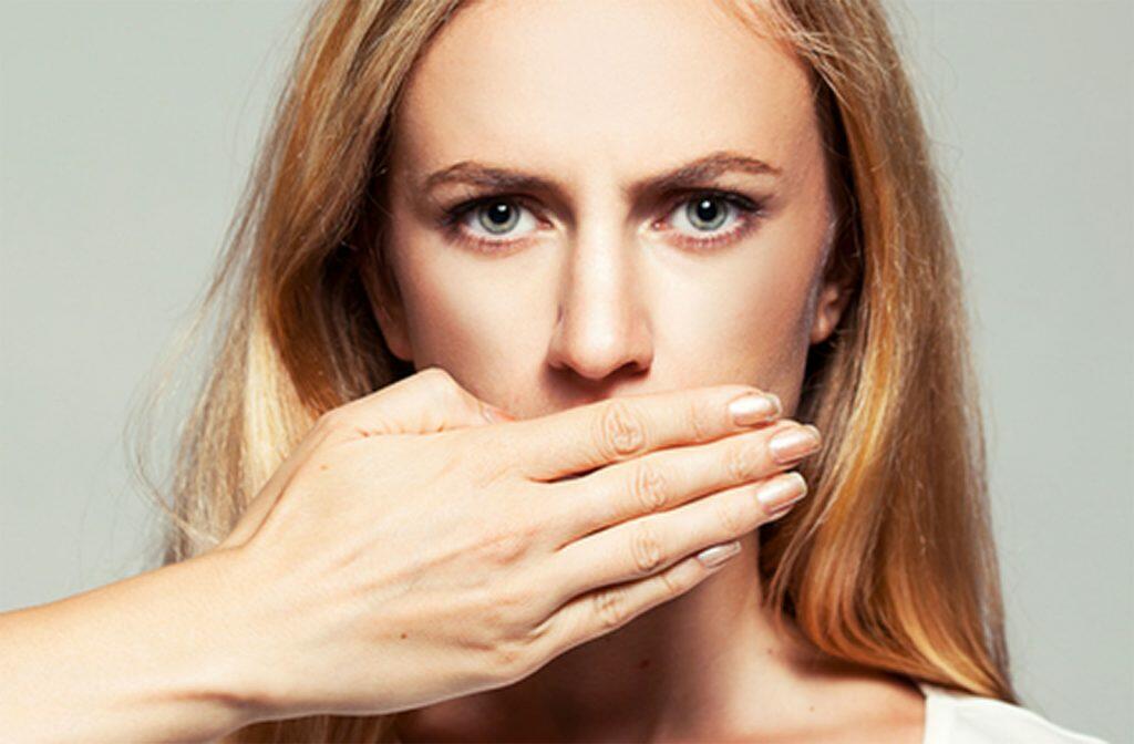 Woman covering mouth smile unhappy with her smile