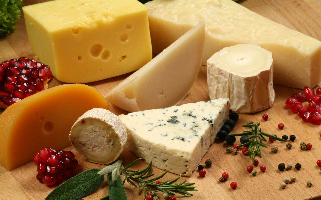 Various types of cheese on a wooden cutting board, perfect for Christmas gatherings or dental health-conscious individuals.