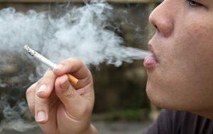 A man smoking a cigarette after a tooth extraction.