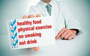 A doctor holding up a sign promoting healthy food, physical exercise, and advising against smoking and excessive drinking as effective dental weapons against sleep apnea.