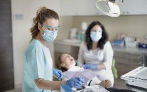 A dental hygienist is examining a patient in a dental office.