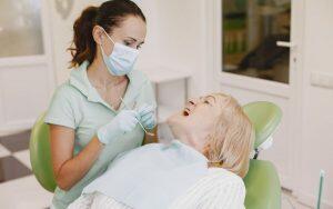 A woman with dementia is seated in a dentist's chair receiving oral health treatment.