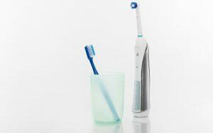 Choosing the right toothbrush by considering the electric option, displayed next to a glass of water.