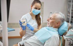 A dentist demonstrating dental care to a patient by showcasing a respiratory system dental model.