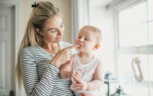 A woman is creatively encouraging a baby to brush his teeth using fun methods.