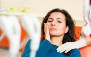 A woman is experiencing a toothache during her visit to the dentist.