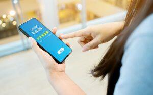 A woman highlights the importance of dentists by pointing at a smartphone with a five star rating on National Dentist's Day.