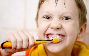 A young boy is brushing his teeth, but making dental hygiene mistakes.