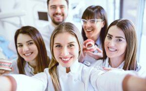 A group of dental professionals practicing good patient care by taking a selfie.