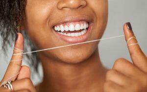 A woman is holding a piece of string in her mouth.