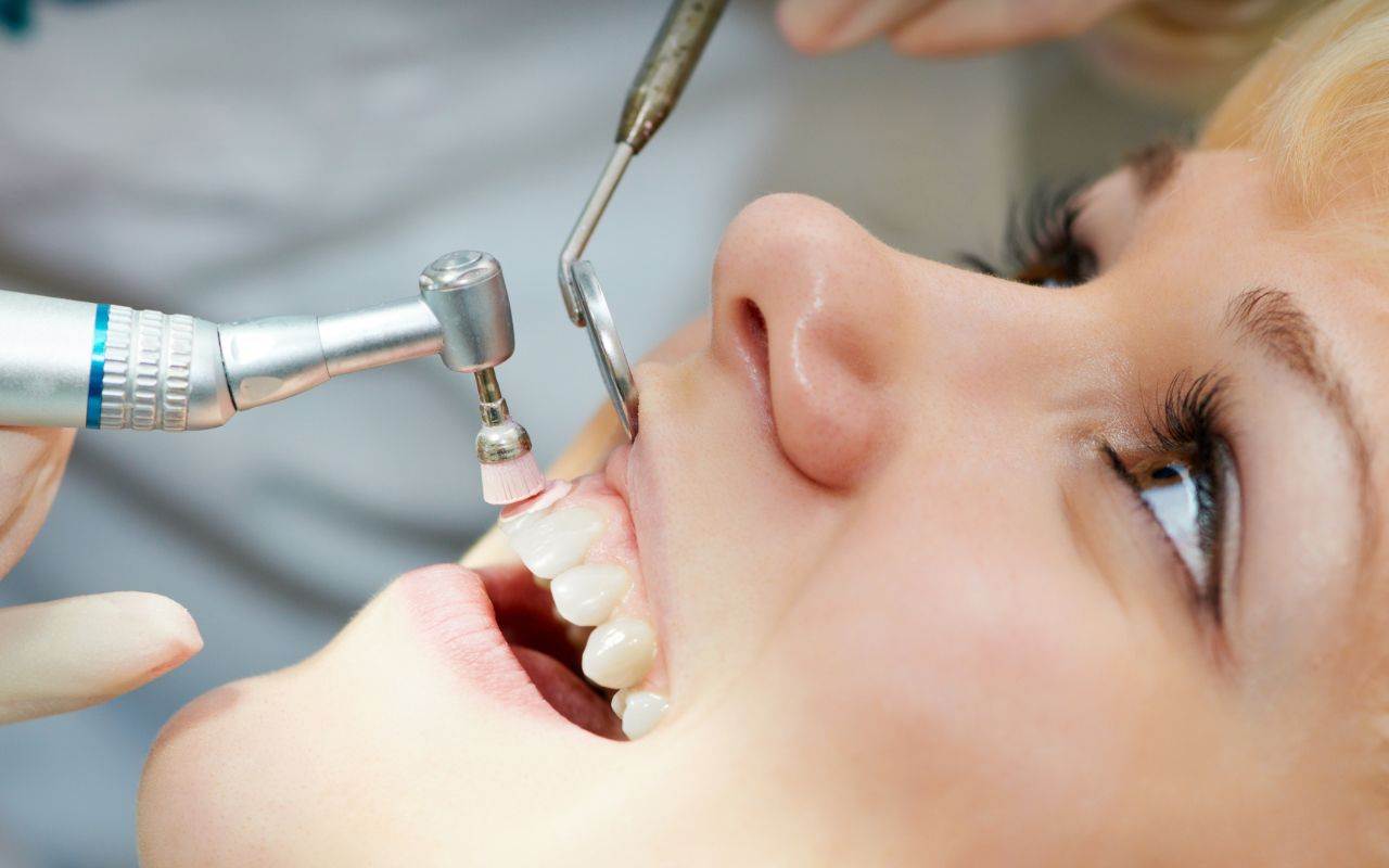 A woman's teeth being cleaned by a dentist.