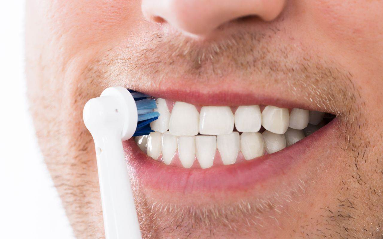 A man is brushing his teeth with a toothbrush.