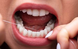 A woman is holding a toothpick in her mouth.