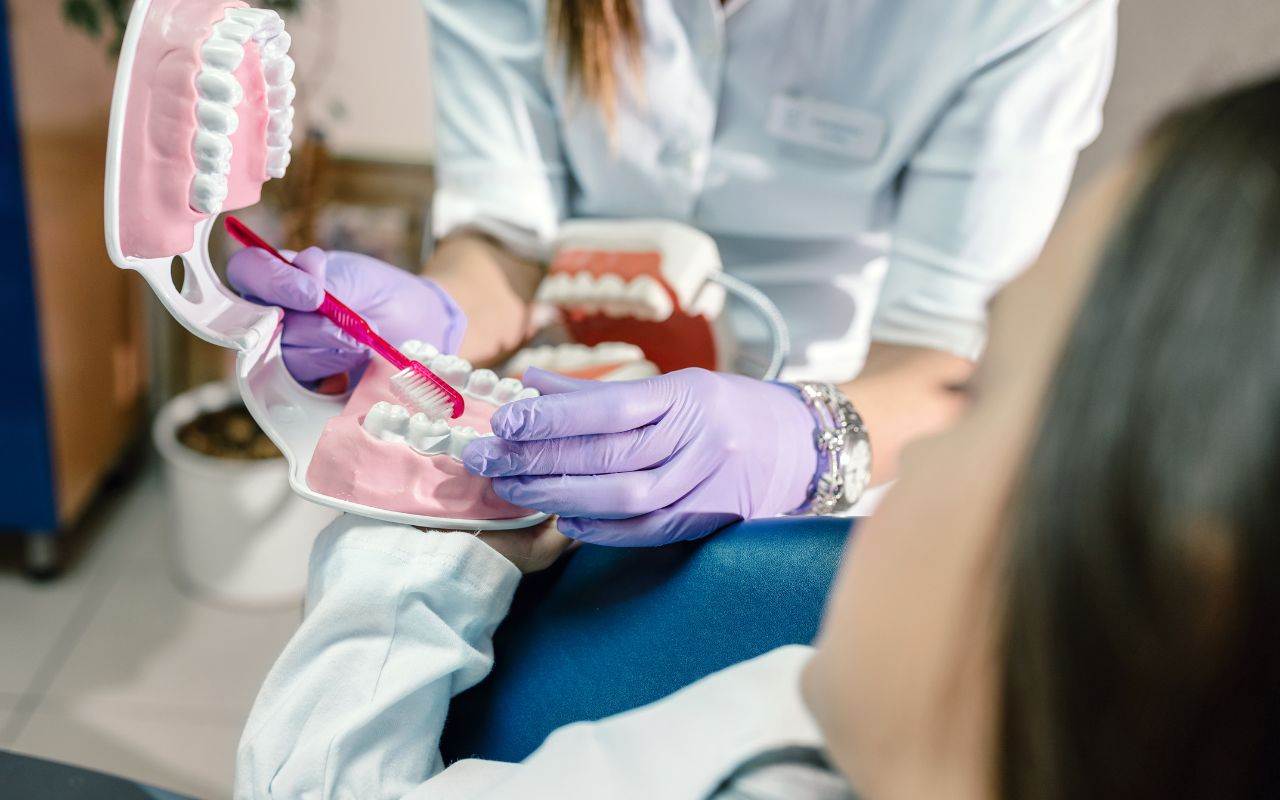 A dentist is instructing a patient on proper brushing technique.