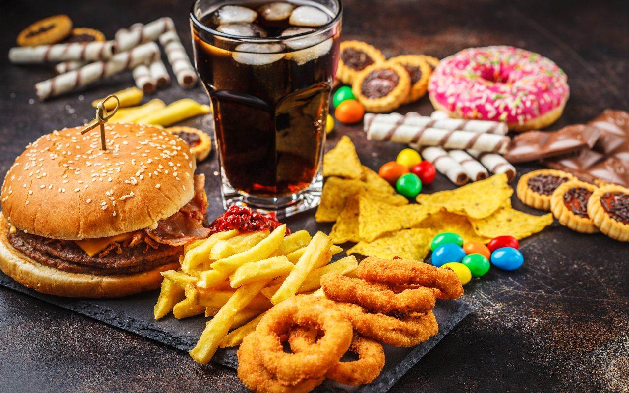 Burgers, fries, soda and snacks on a table - avoid-unhealthy-snacks-and-food-like-sugar-and-refined-carbohydrates