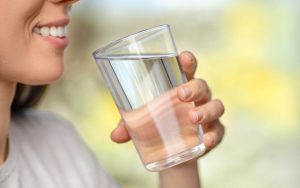 A woman is holding a glass of water.